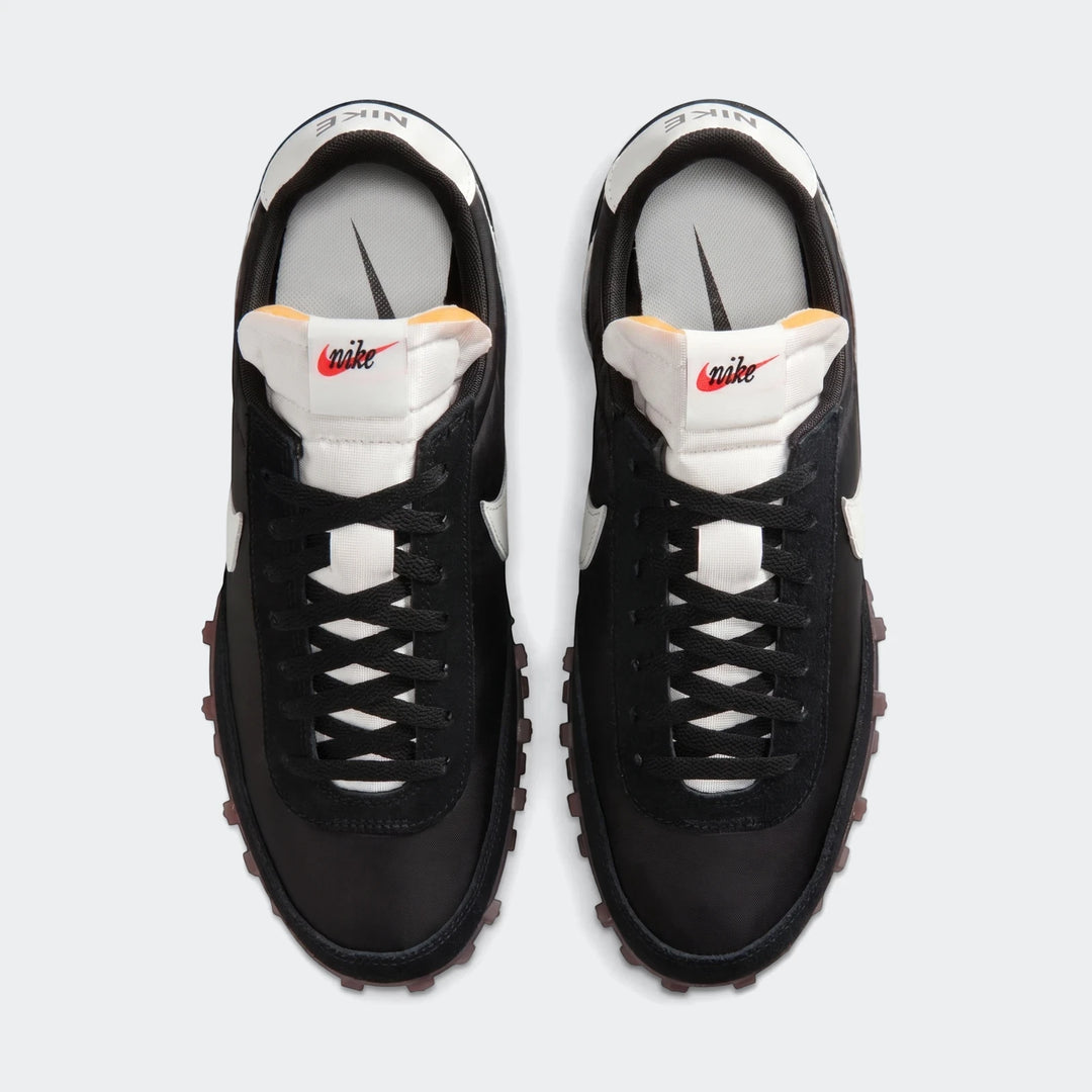 Top-down view of a pair of Nike Waffle Racer men's shoes in black and white, featuring black laces and brown waffle outsoles.