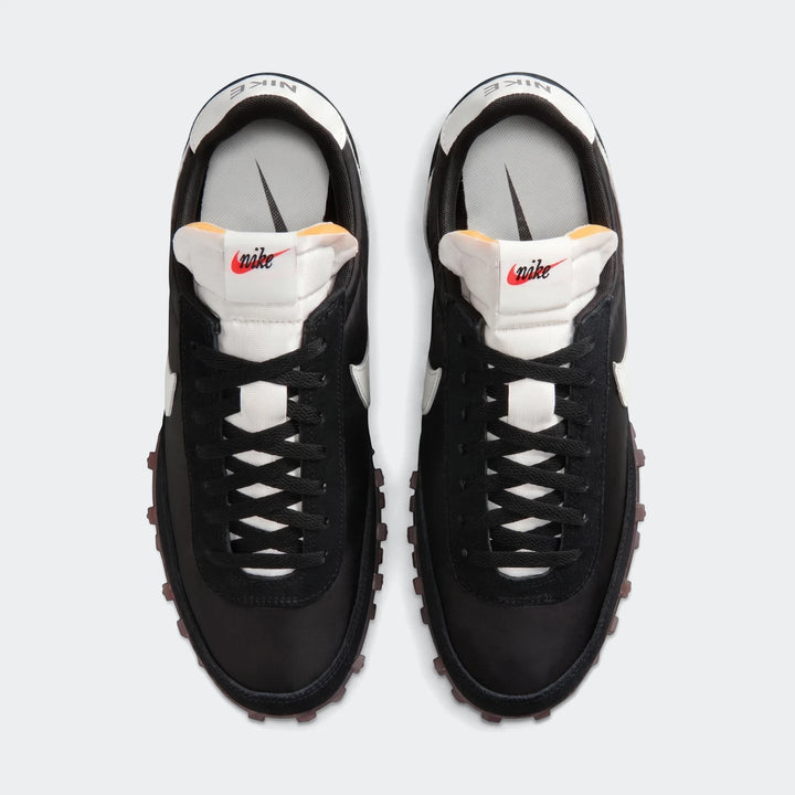 Top-down view of a pair of Nike Waffle Racer men's shoes in black and white, featuring black laces and brown waffle outsoles.