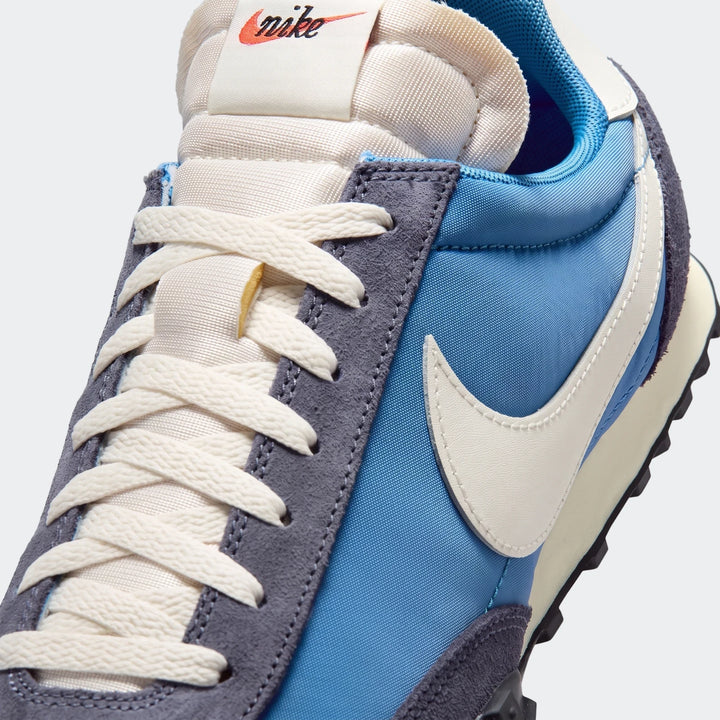 Close-up of a blue and grey Nike Waffle Racer men's shoe with cream laces and a prominent white swoosh.