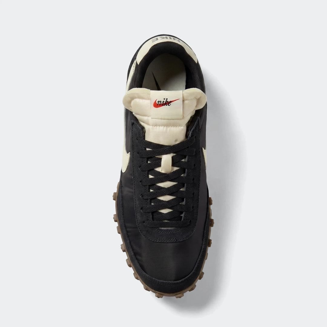 Overhead view of a black and cream Nike Waffle Racer men's shoe with a textured brown sole and black laces.