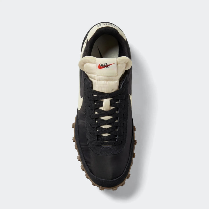 Overhead view of a black and cream Nike Waffle Racer men's shoe with a textured brown sole and black laces.