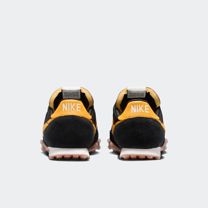 Back view of two Nike Waffle Racer men's shoes in black and yellow with suede uppers, white Nike logo, and waffle outsoles.
