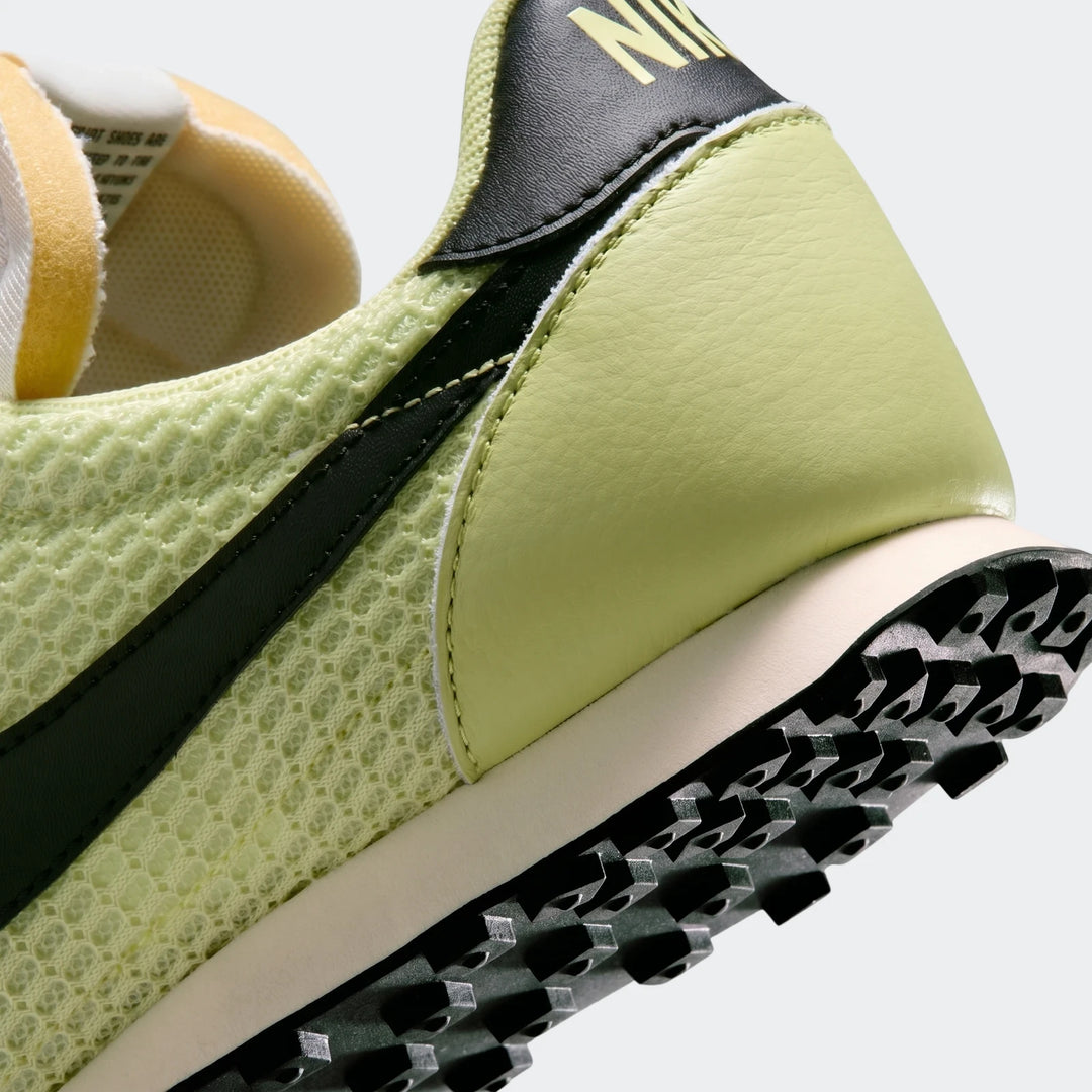 A close-up view of the back and side of a Nike Waffle Racer SE men's shoe in lime green mesh and leather, featuring a black