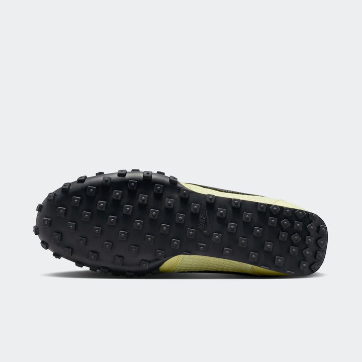 Bottom view of a Nike Waffle Racer SE men's shoe, featuring a green upper and a black rubber waffle outsole.