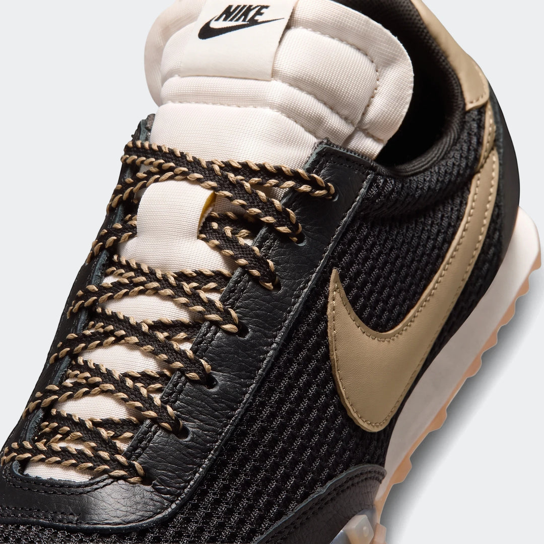 Close-up of a black and beige Nike Waffle Racer SE men's shoe, featuring textured mesh, leather overlays, two-tone laces,