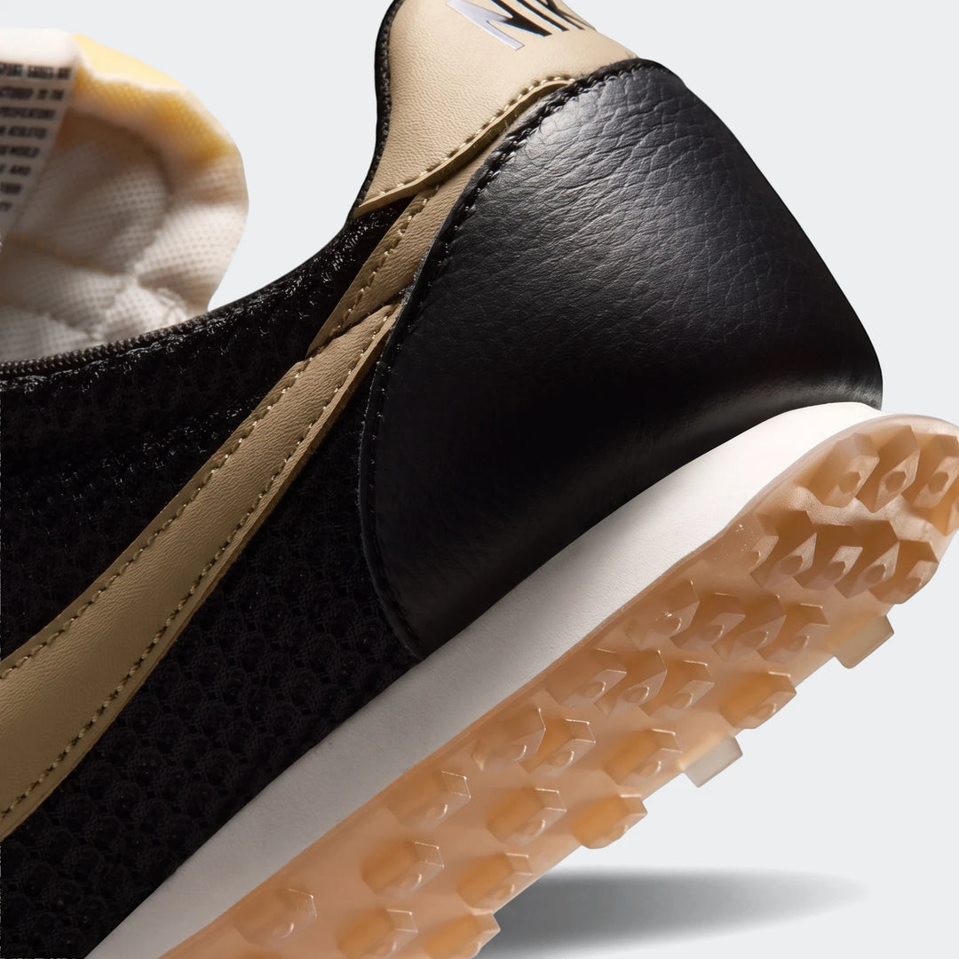 Close-up of a black and tan Nike Waffle Racer Se Men's shoe, angled to show the textured heel, side profile, and distinctive