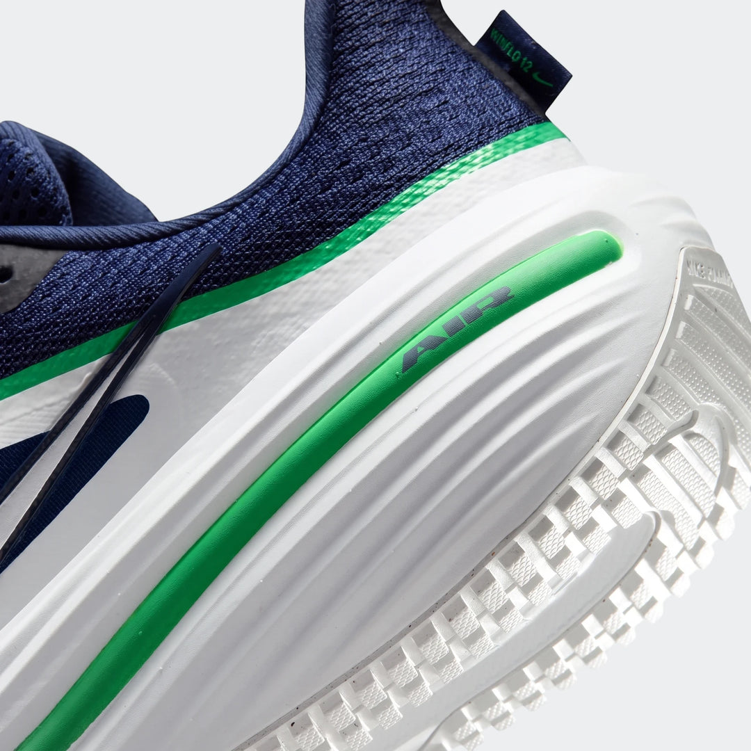 Close-up of Nike Winflo 12 men's road running shoe, featuring navy blue knitted upper, white midsole, and green accent
