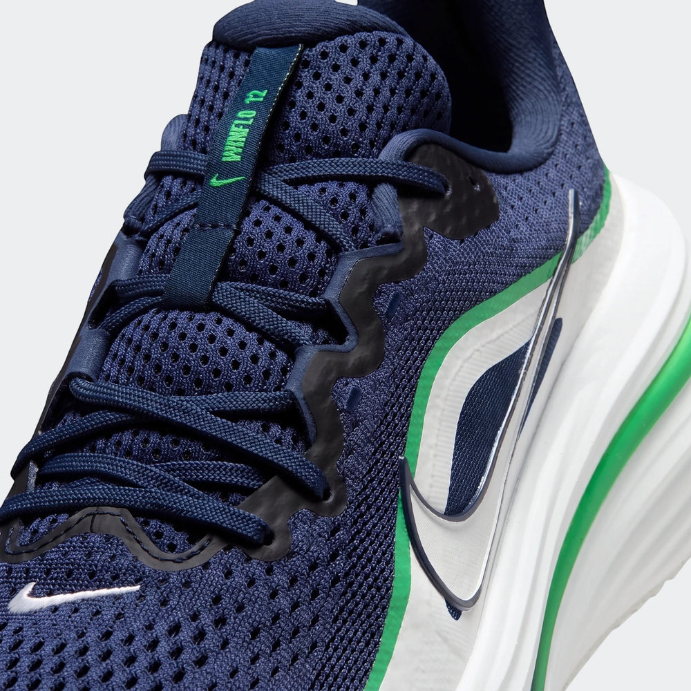 Close-up of a navy blue Nike Winflo 12 Men's Road Running Shoe with green and white accents, showing the mesh upper, laces,