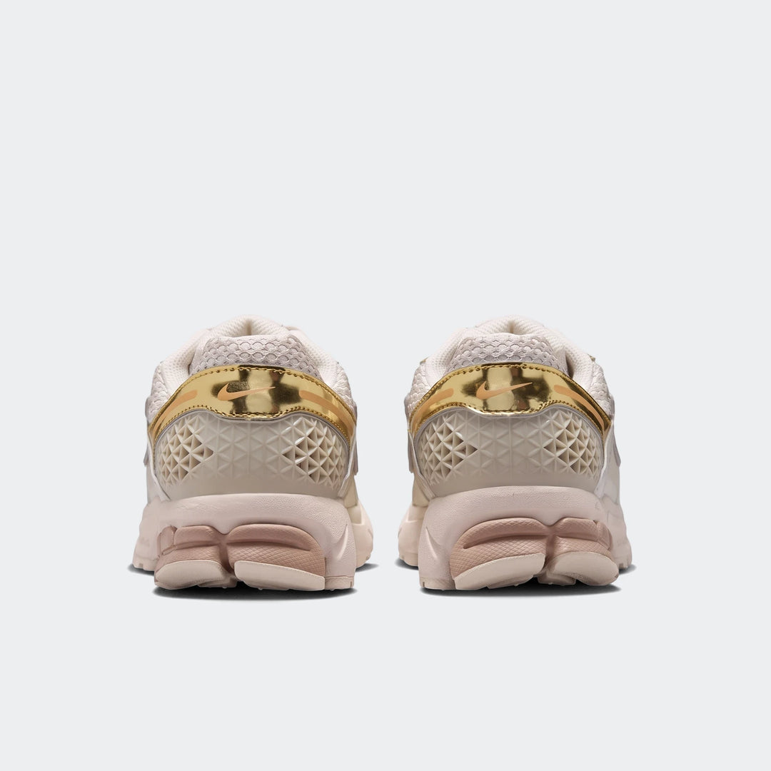 Rear view of two Nike Zoom Vomero 5 Women's Shoes in cream and gold, showcasing the textured heel and multi-layered sole.