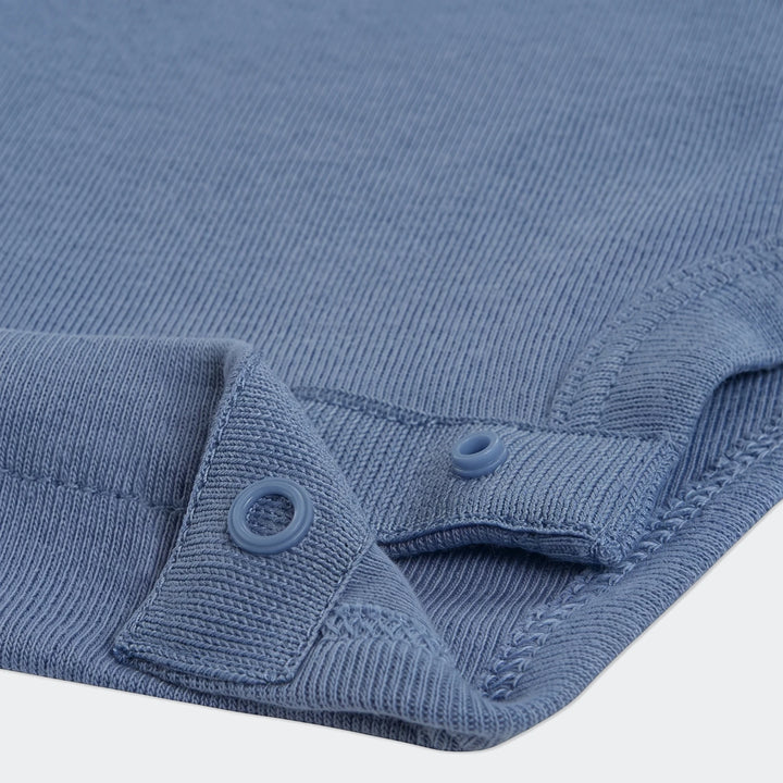 Close-up of the blue knit fabric from Nkn Essentials 3Pc Pant Set, featuring snap buttons and ribbed texture.