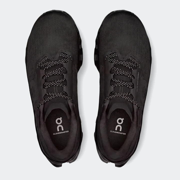Pair of black On Running Cloudmonster 3 men's running sneakers with white speckled laces, viewed from above.