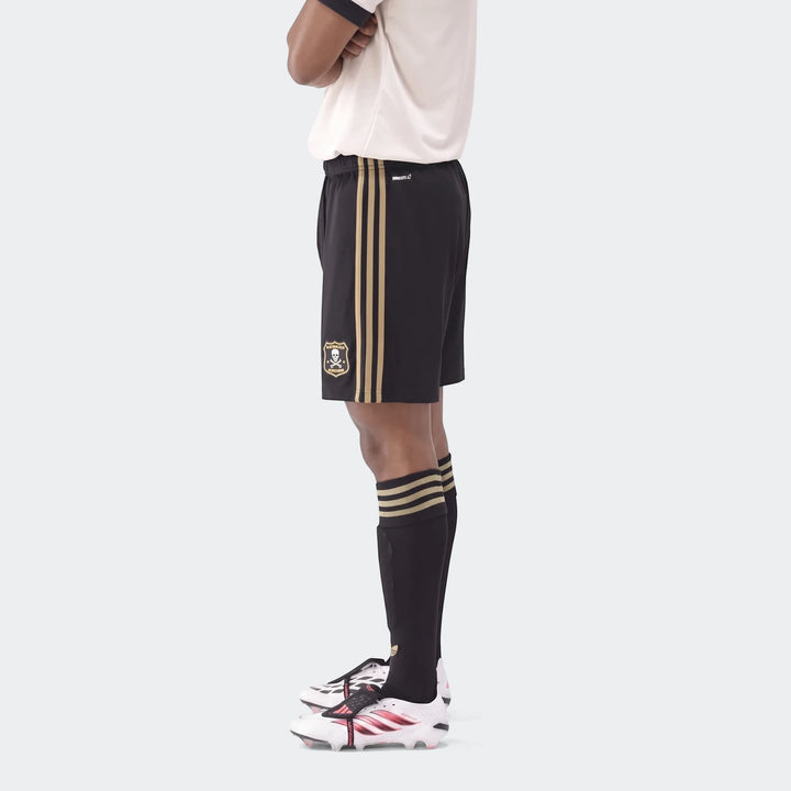 Op A Sho men's soccer uniform, featuring black shorts with gold stripes, white shirt, black socks, and white cleats, shown