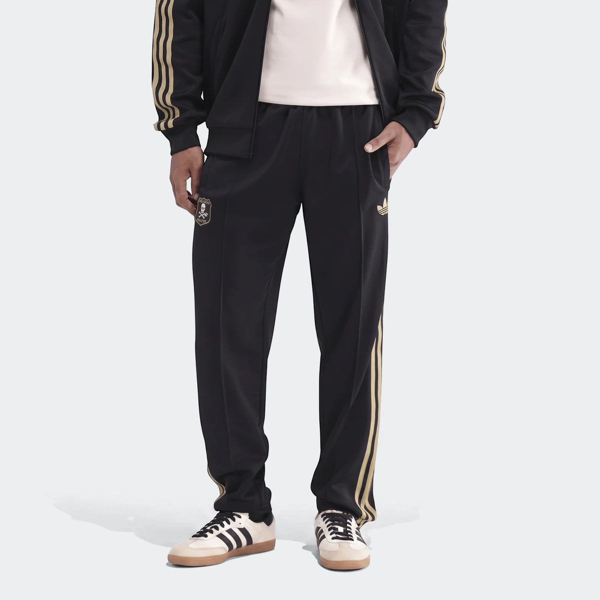 Op Og2 Tp men's black tracksuit pants with gold stripes, an Adidas logo, and Orlando Pirates FC crest worn by a model.