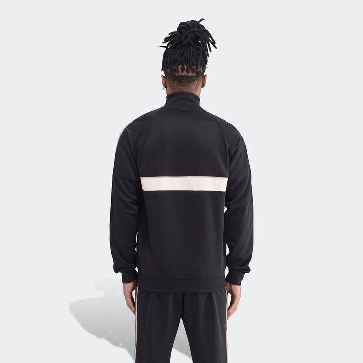 Back view of a male model wearing the black Op Og2 Tt track jacket with white and gold stripes, paired with matching track