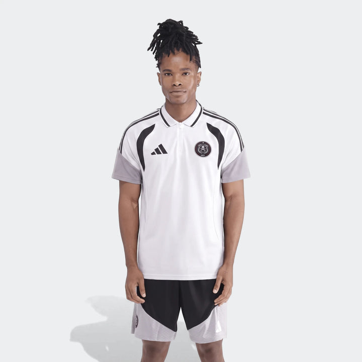 Male model wearing an adidas Op Tiro26C Polo in white with black accents and matching black and grey athletic shorts.