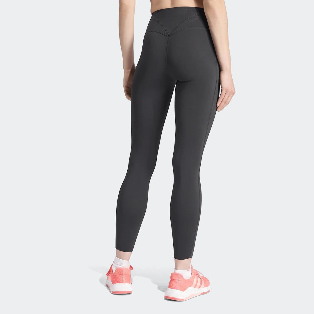 A woman from the back wearing dark gray Optime Workout Contour Full Length Leggings and pink sneakers.