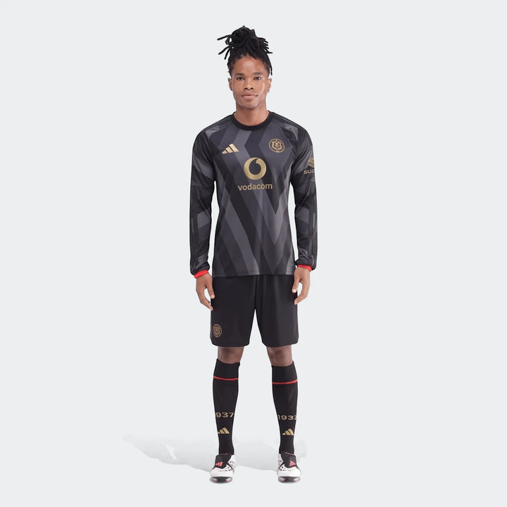Male model wearing the Orlando Pirates 26/27 Home Jersey full kit, a black and grey patterned long-sleeve top with shorts