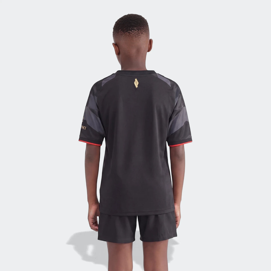 Back view of a young boy wearing an Orlando Pirates 26/27 Home Kids Jersey, featuring black, gray, and red design with a