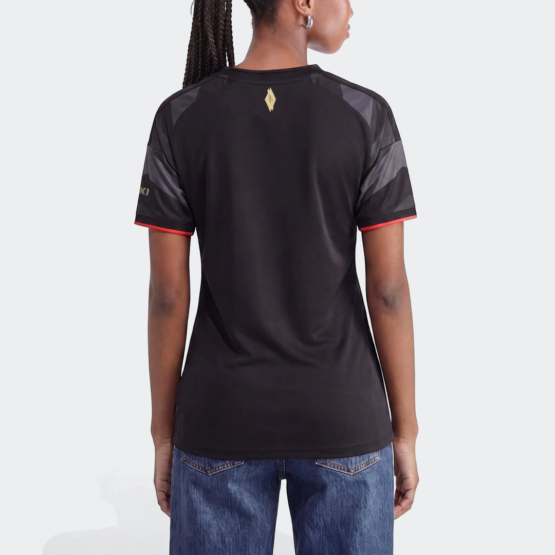 Back view of a woman wearing a black Orlando Pirates 26/27 Home Jersey with red and grey details and blue jeans.