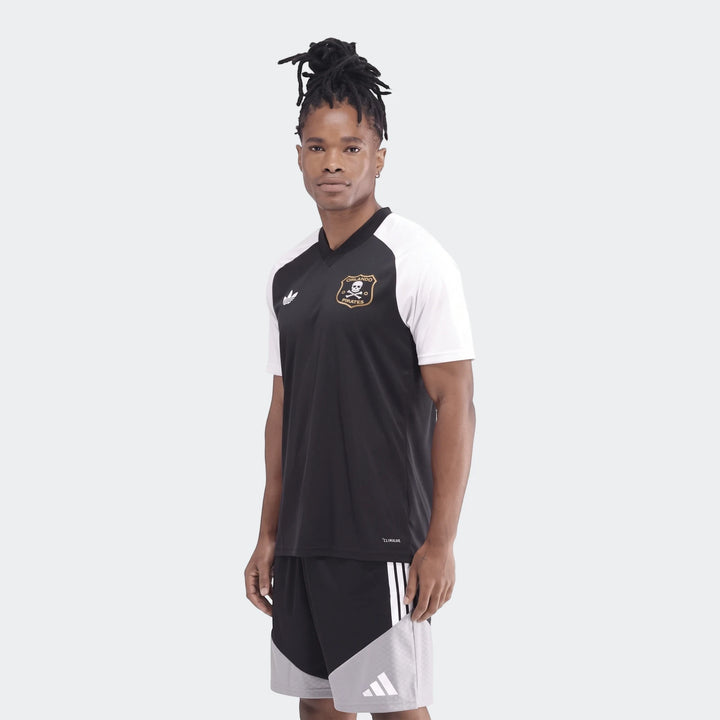 Young man with dreadlocks wearing a black and white Adidas Orlando Pirates 26 Pre Match Trefoil Jersey and shorts.