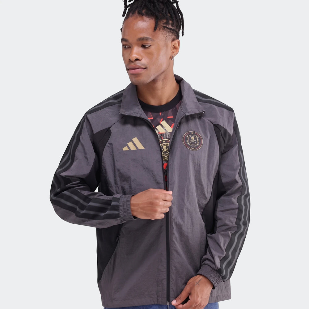 Male model wears an Adidas Orlando Pirates Home Anthem Jacket in dark grey with black stripes and gold logos.