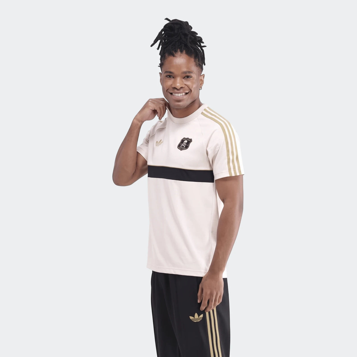 Men's Orlando Pirates Originals T-shirt in cream, black, and gold with Adidas logo, worn by a smiling model.