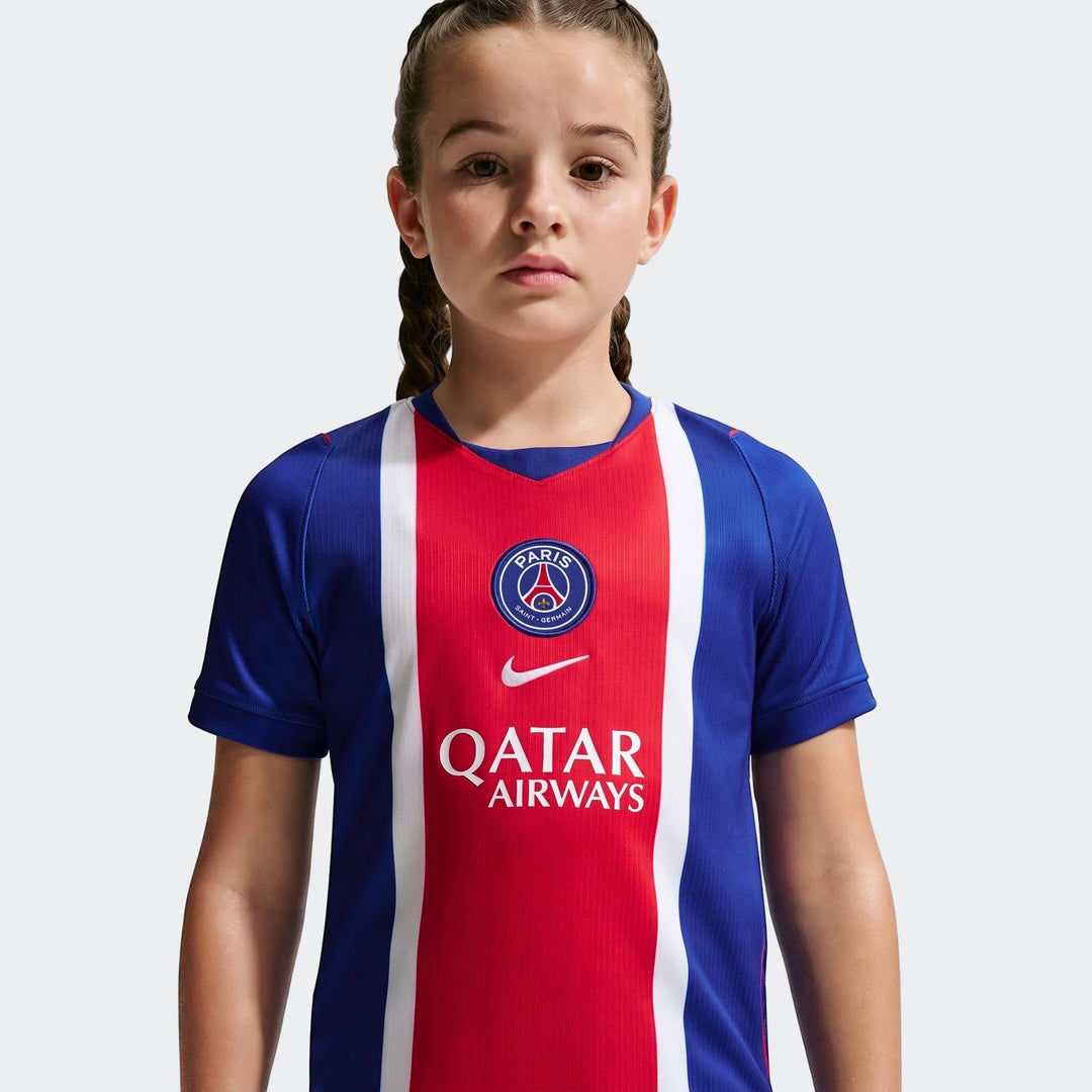 Young girl models a Paris Saint-Germain 2026/27 Stadium Home Big Kids' Nike Dri-Fit Soccer Replica Jersey in blue, red, and