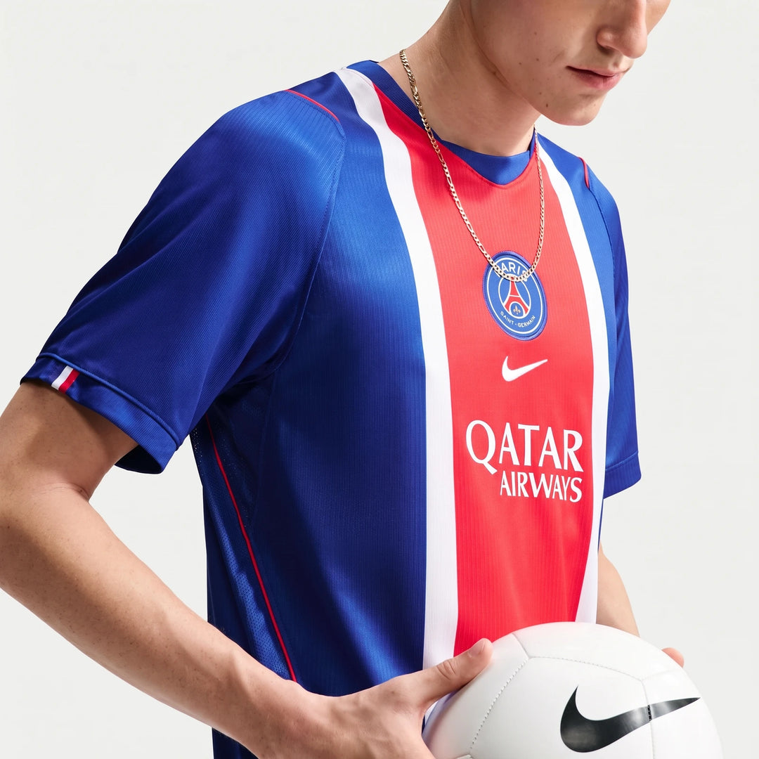 Person wearing a blue, red, and white Paris Saint-Germain 2026/27 Stadium Home Men's Nike Dri-Fit Soccer Replica Jersey,