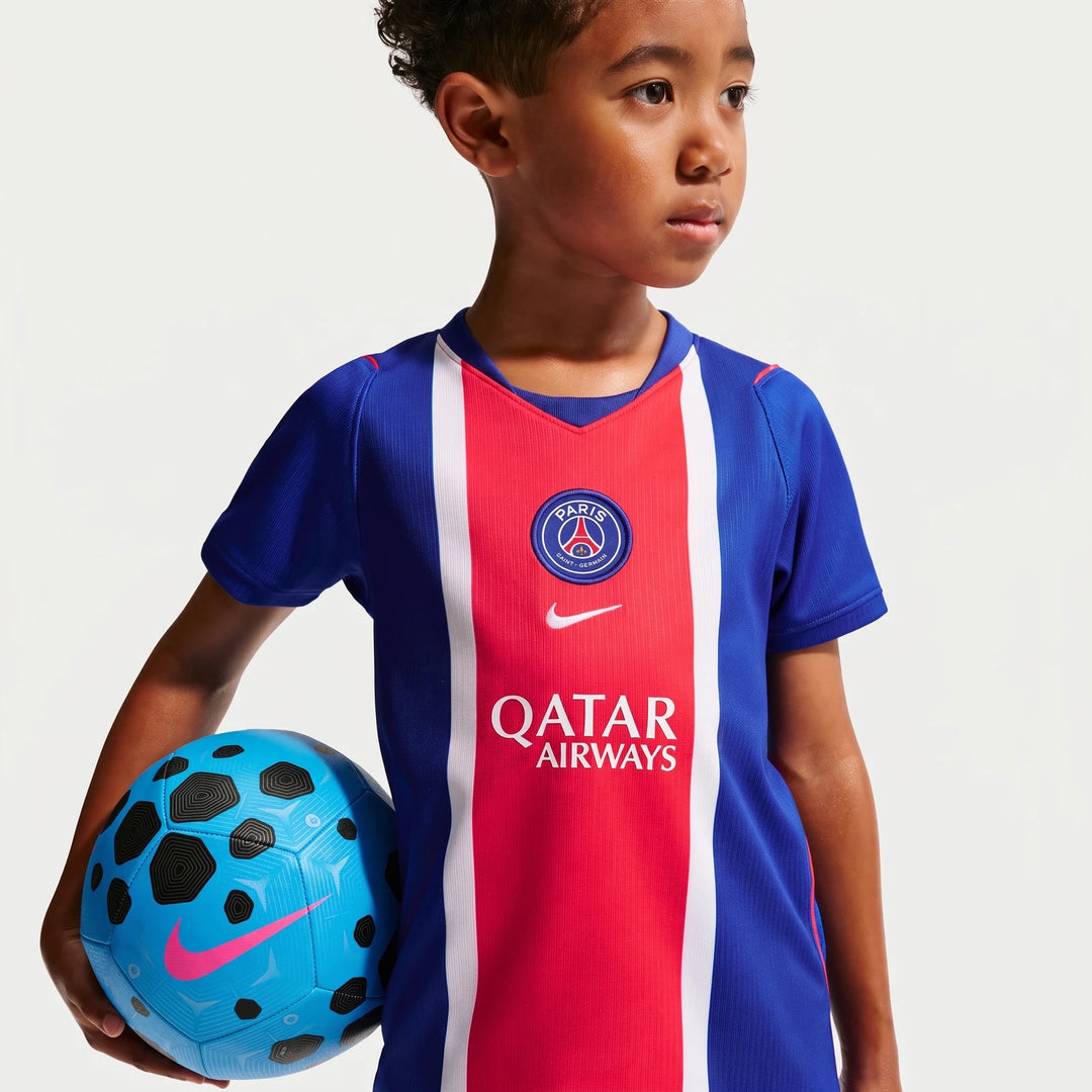 Young boy wearing a blue, red, and white Paris Saint-Germain 2026 Stadium Home Nike Soccer Replica jersey, holding a blue