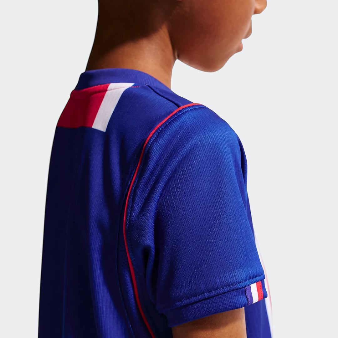 Close-up of a child wearing a blue Paris Saint-Germain 2026 Stadium Home Nike Soccer Replica jersey with red and white