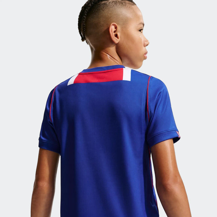 Back view of a boy wearing a blue Paris Saint-Germain 2026/27 Stadium Home Big Kids' Nike Dri-Fit Soccer Replica Jersey with