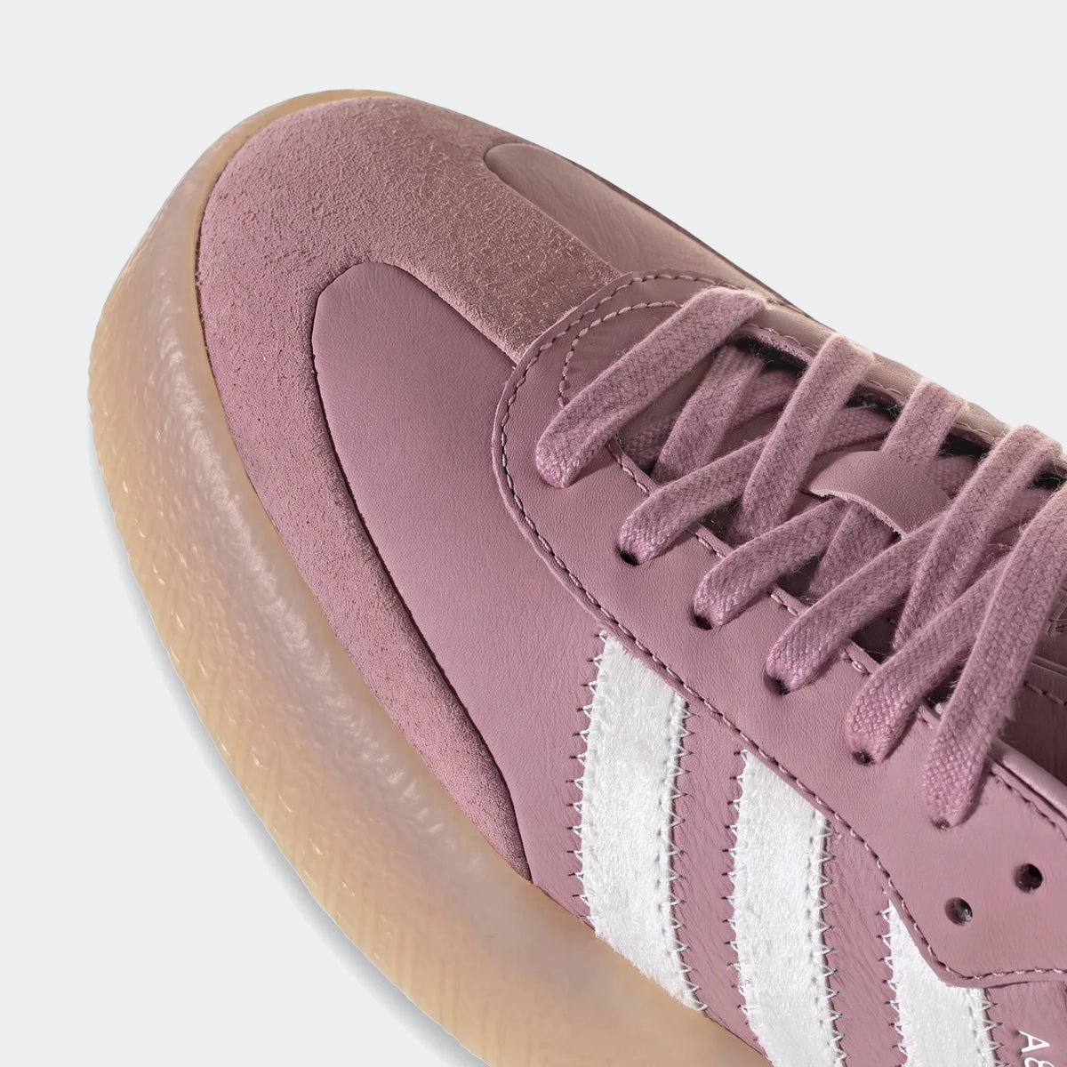 Close-up angled view of a pink Sambae shoe featuring white Adidas stripes, suede and synthetic leather upper, and a gum sole.