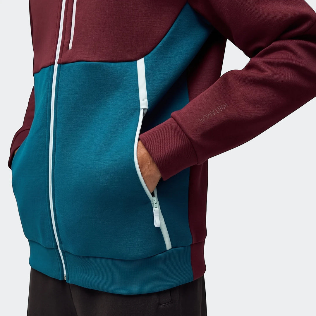 Close-up of a men's Portugal Pumatech full-zip hoodie in maroon and teal with a hand in the zippered pocket.