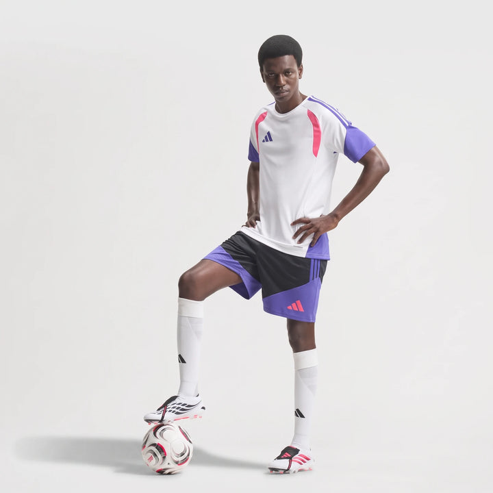 Male model wearing Predator Elite Fold-Over Tongue Firm Ground Football Boots with a white and purple football kit, foot