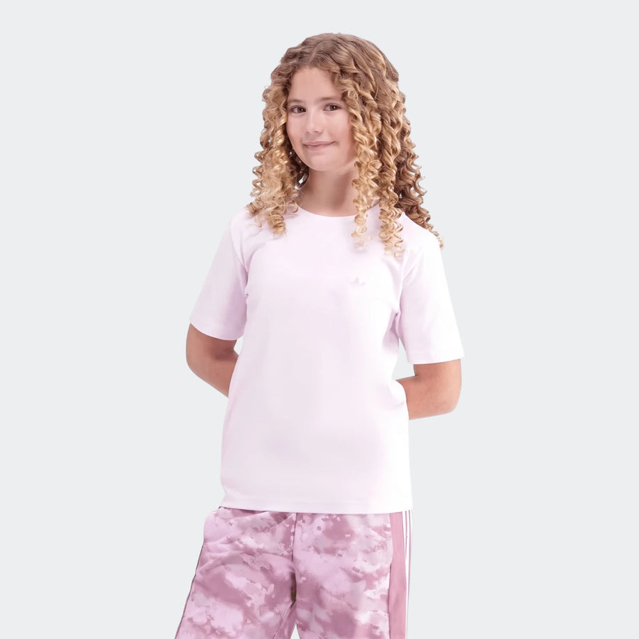Young girl wearing a pink Premium Essentials Tee and pink patterned shorts, with curly hair. Front view.