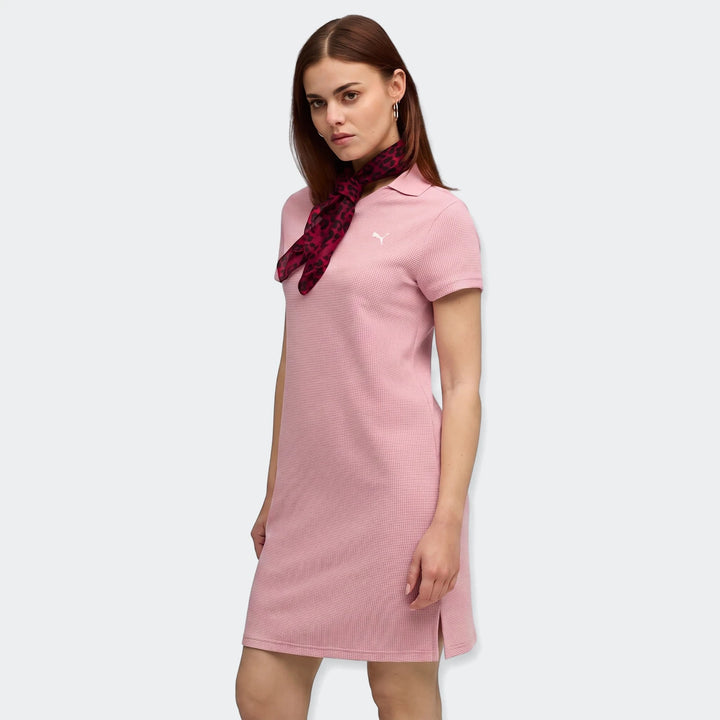 Woman models a pink Puma Class Pinnacle Dress with a collared neck, short sleeves, and a red leopard print scarf.