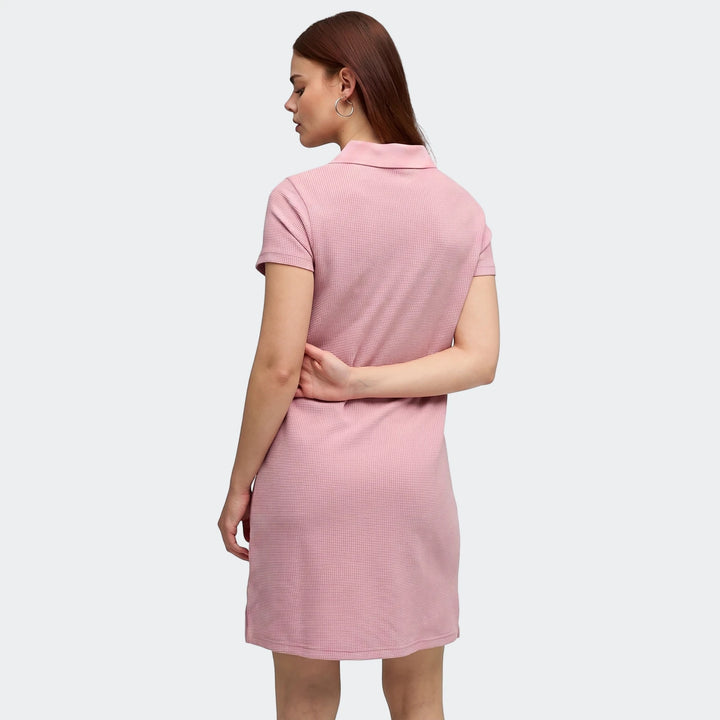 Pink waffle-knit Puma Class Pinnacle Dress on a woman from the back, featuring a polo collar and short sleeves.