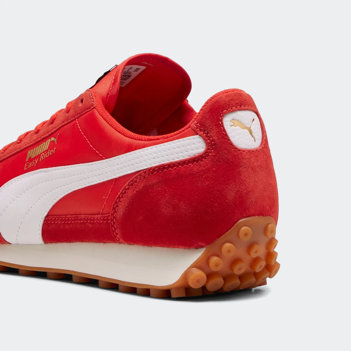 Close-up of a red Puma Easy Rider Kids PS sneaker with satin-like upper, suede overlays, white stripe, and brown rubber