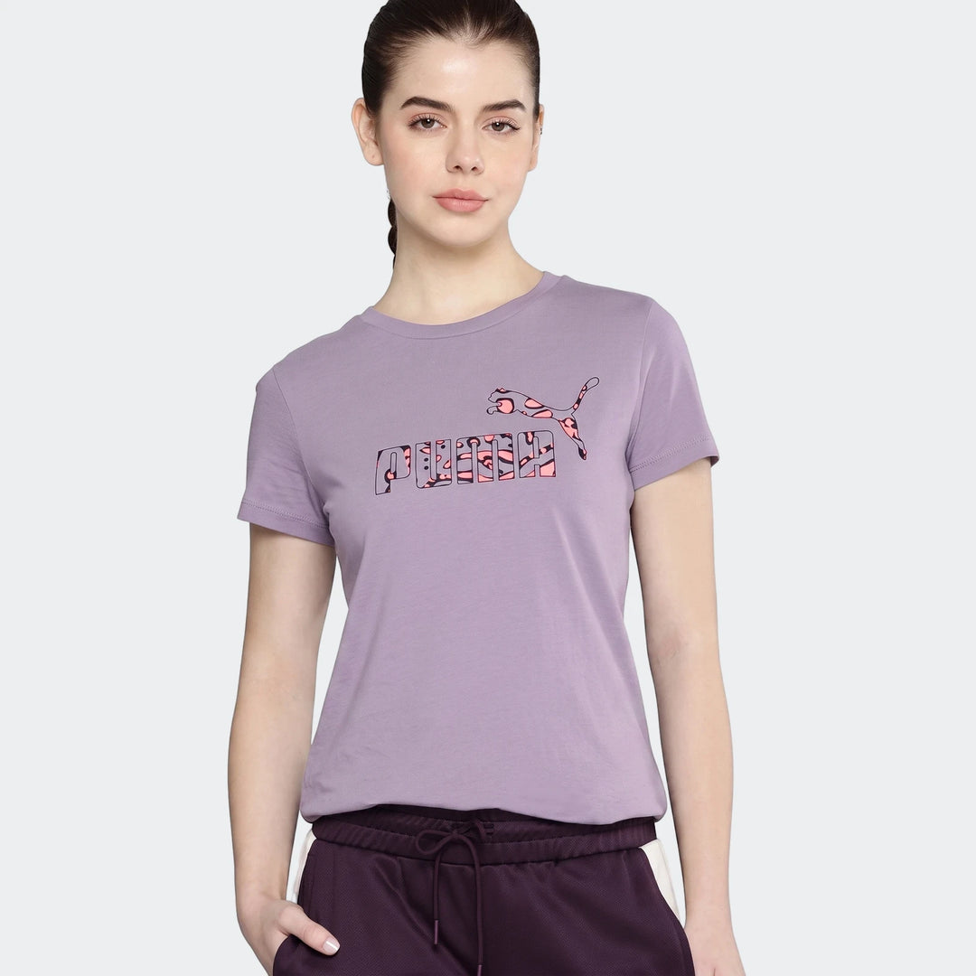 Young woman wearing a Puma Power Hypernatural purple t-shirt with a patterned logo and dark joggers, standing against a grey