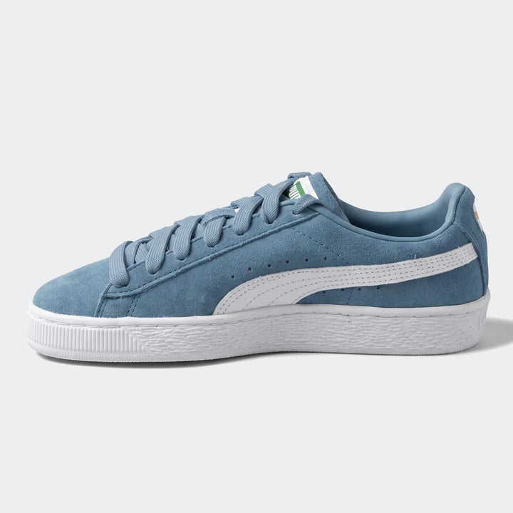 Blue suede Puma Suede Classic low-top sneakers with white laces, a white sole, and a white formstrip, viewed from the side.