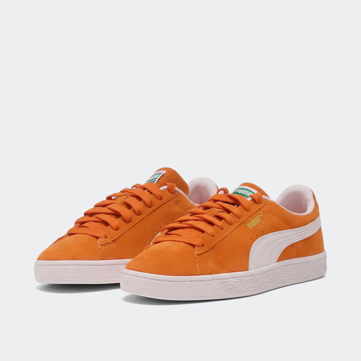Pair of orange Suede Classic Cayenne Pepper Puma sneakers with white Formstrip, laces, and sole, angled slightly.