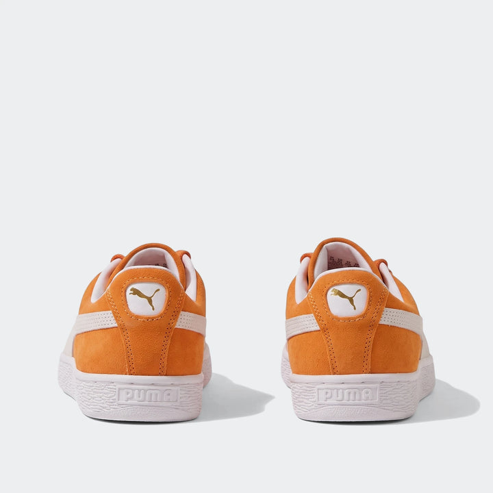 Two Puma Suede Classic unisex sneakers in cayenne pepper orange suede with white Formstrips and soles, viewed from the back.