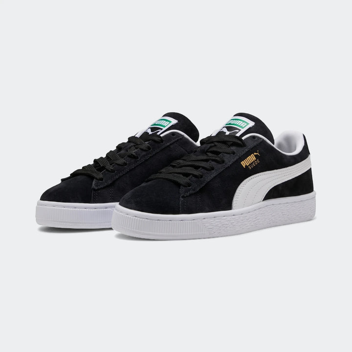 Pair of black suede Puma Suede Classic youth sneakers with white soles and stripes on a white background.