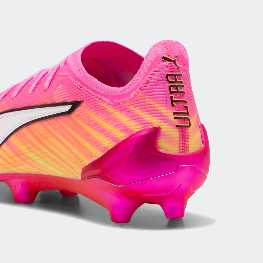Close-up side view of a pink and yellow Puma Ultra 6 Ultimate FG football boot with white branding.