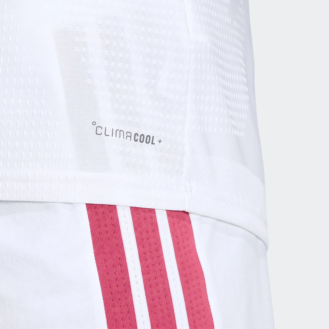 Close-up of a white Real Madrid 25/26 Authentic Home Jersey with CLIMACOOL+ logo and pink-striped white shorts.