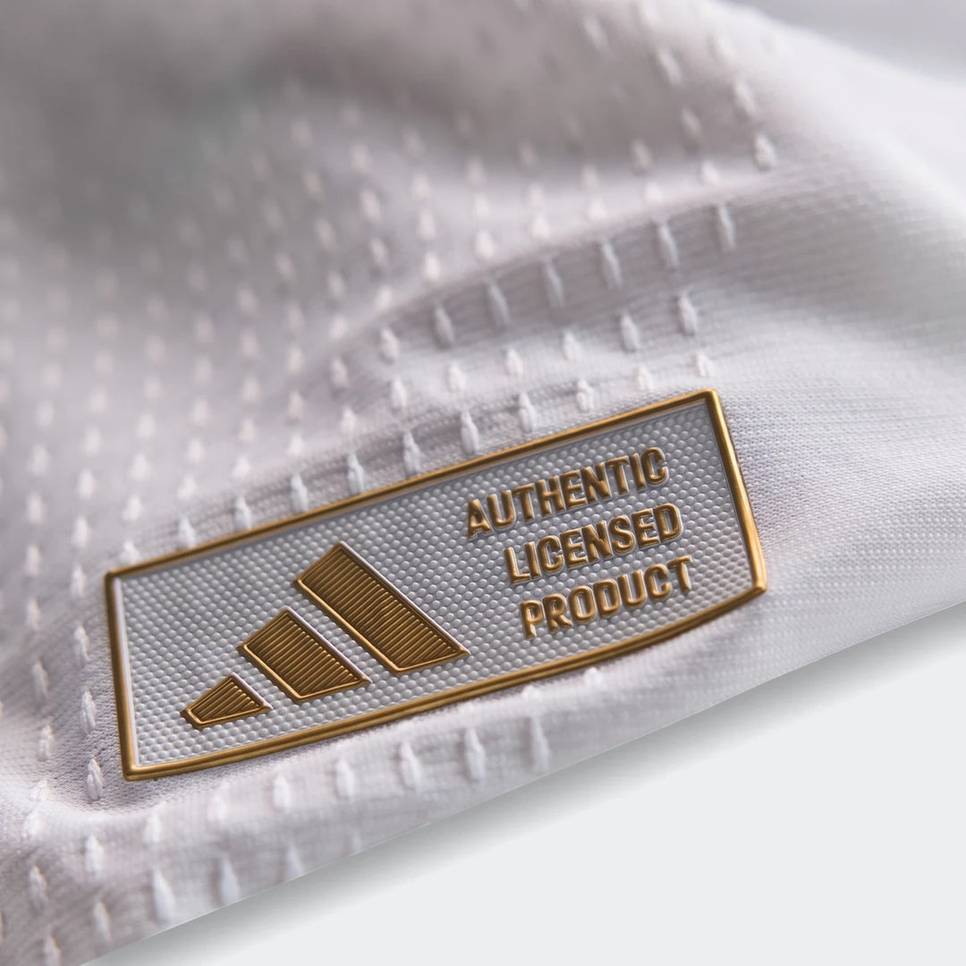 Close-up of the Adidas 'Authentic Licensed Product' tag on a white Real Madrid 25/26 Authentic Home Jersey, showcasing