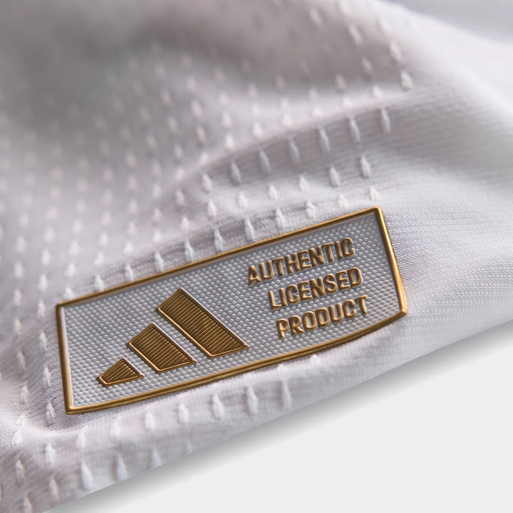 Close-up of the Adidas 'Authentic Licensed Product' tag on a white Real Madrid 25/26 Authentic Home Jersey, showcasing