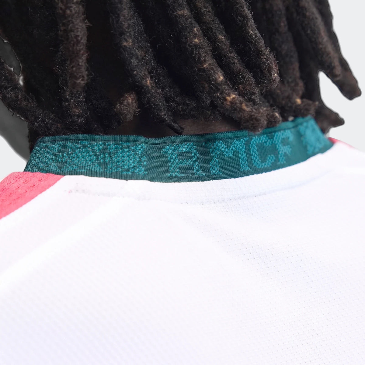 Close-up of the Real Madrid 25/26 Authentic Home Jersey, white with a distinctive green ribbed collar, as worn by a person