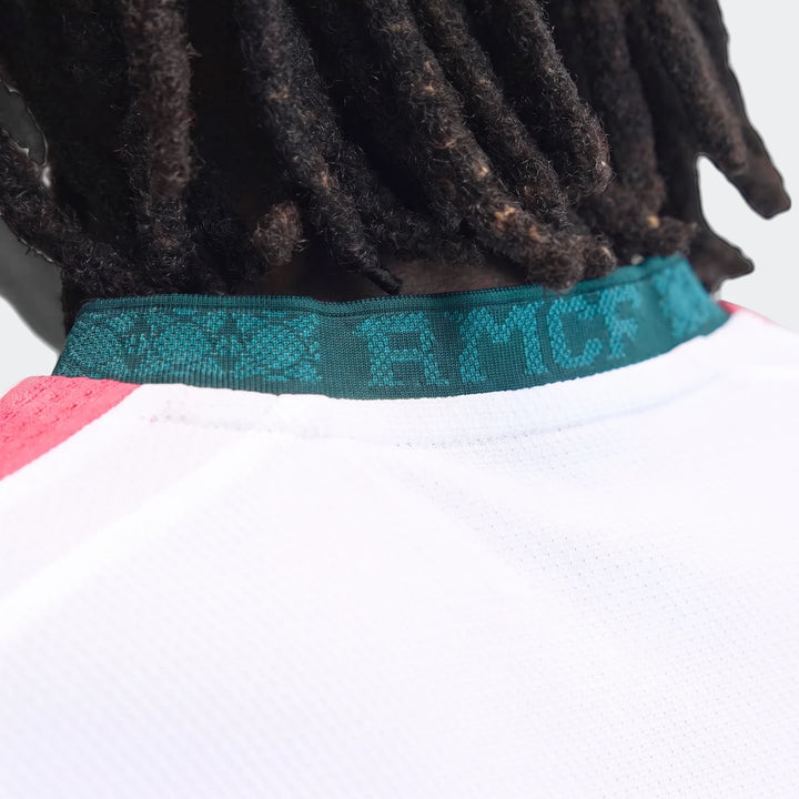 Close-up of the Real Madrid 25/26 Authentic Home Jersey, white with a distinctive green ribbed collar, as worn by a person
