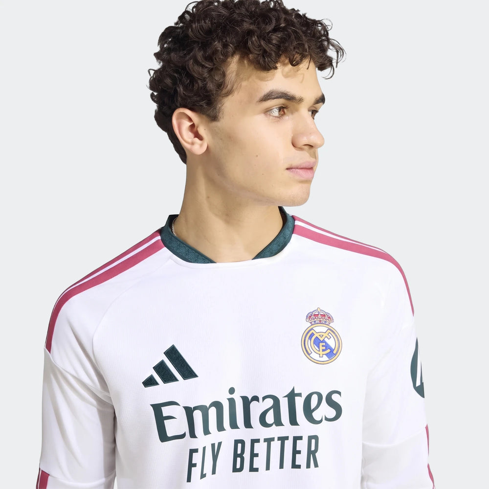 Close-up of a male model wearing the white Real Madrid 25/26 long-sleeve home jersey with team crest and sponsor logo.
